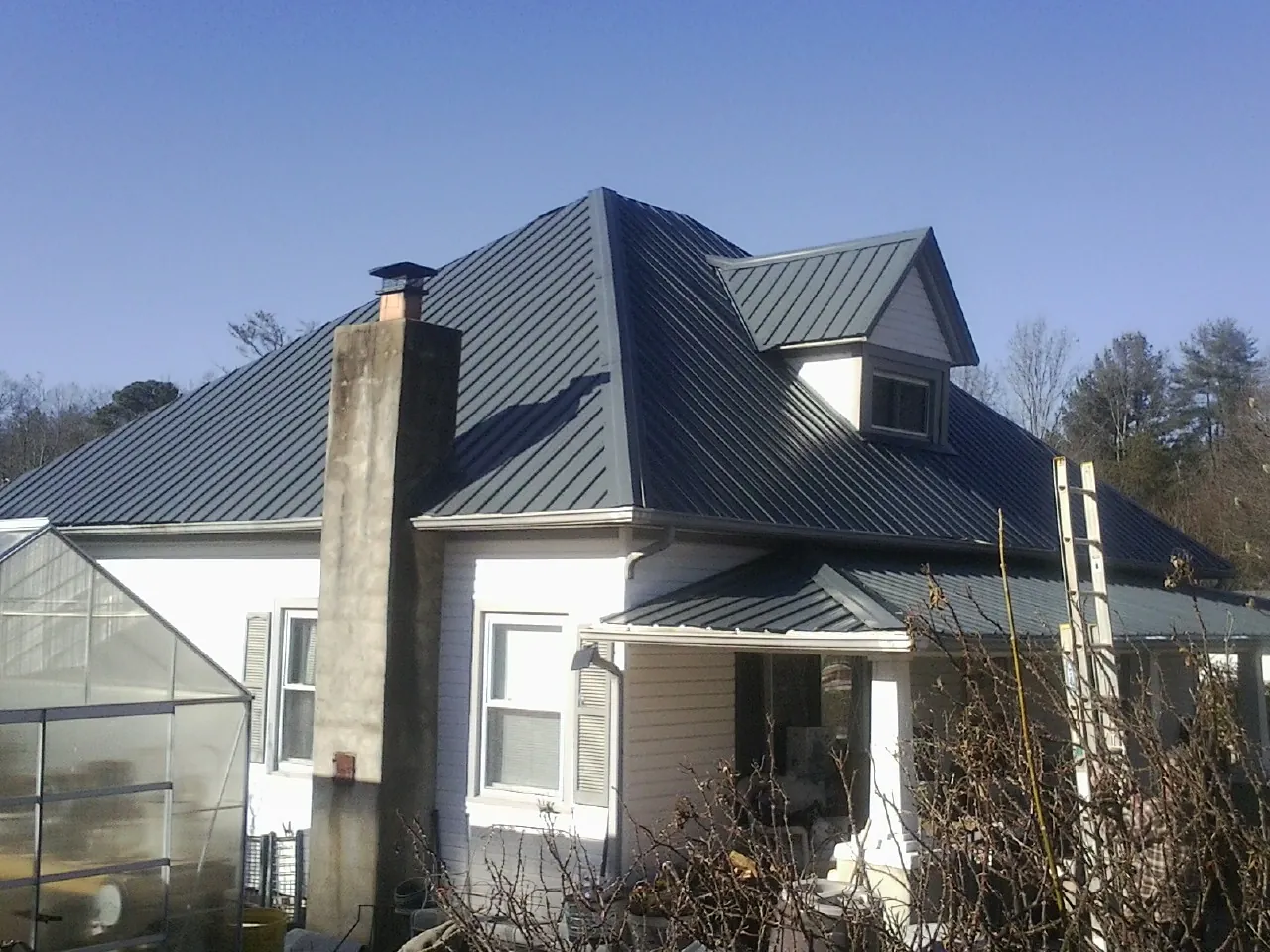 Dark blue standing seam metal roof on a white farmhouse with dormer — Slate & Tile Roof Repair by Roofing Brothers in Bothell