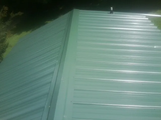 New green metal panels meeting at the ridge of a roof — Flat Roof Repair work by our crew in Bothell