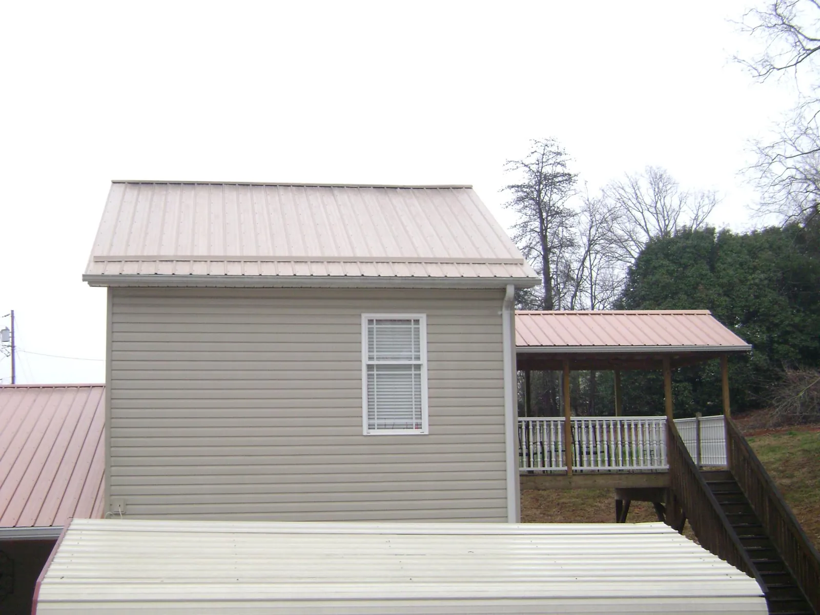 Tan metal roofs on a two story addition and attached porch, from a Roof Replacement job in Bothell