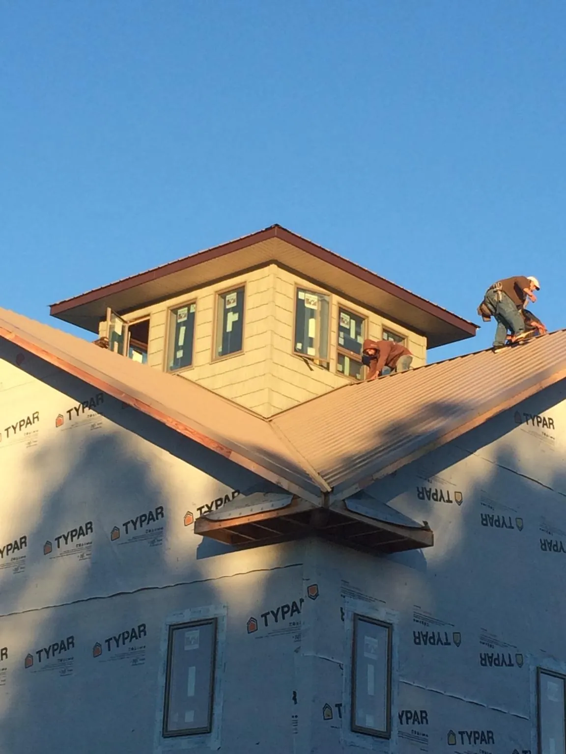 Roofers working around a rooftop cupola on a new metal roof at sunset — Roof Waterproofing in Bothell by Roofing Brothers